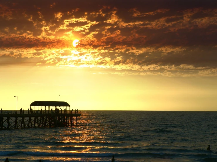 a dock and an umbrella at the beach at sunset