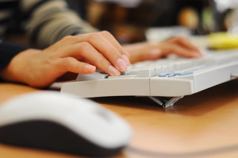 a hand on a keyboard that is on top of a wooden desk