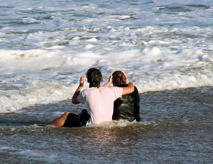 two men in the water sitting back to back