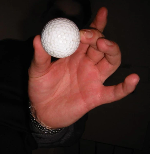 a man holding a white ball in the palm of his hand