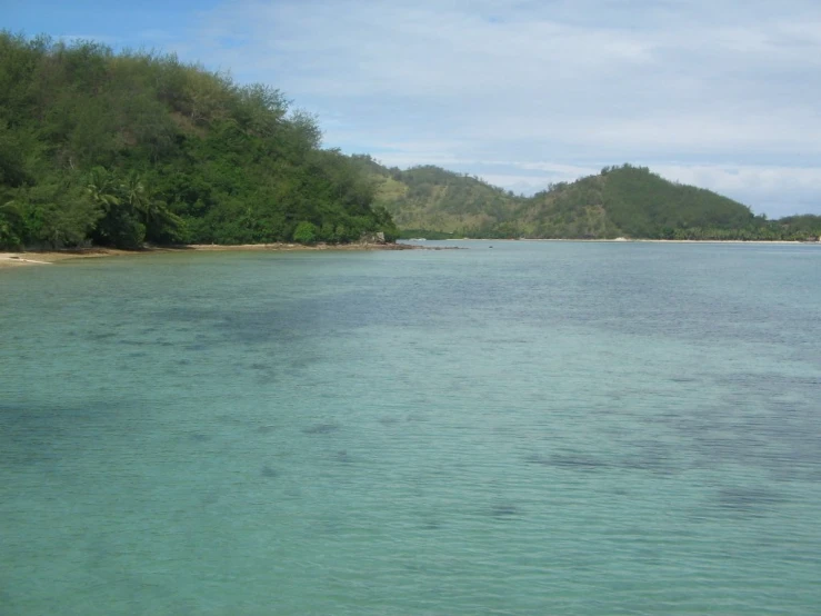 calm waters off the coast with trees and hills in the background