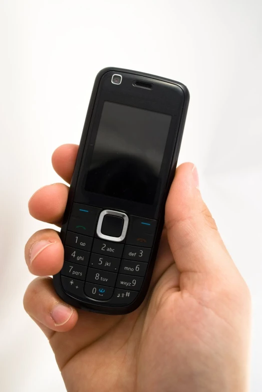 the hand of a person holding a small cell phone
