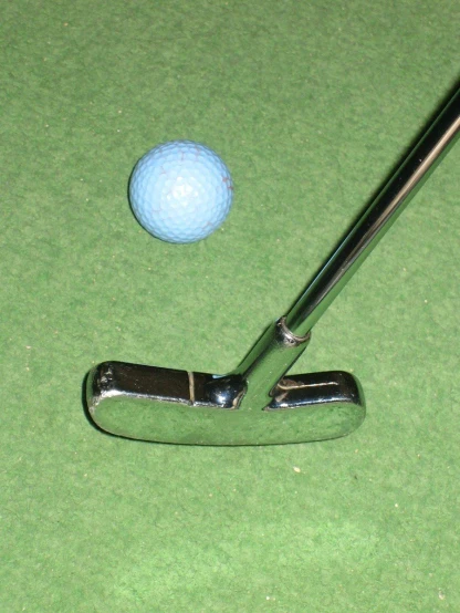 a golf ball is next to a putter