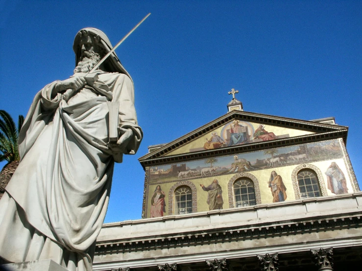 the statue is holding a sword near a church