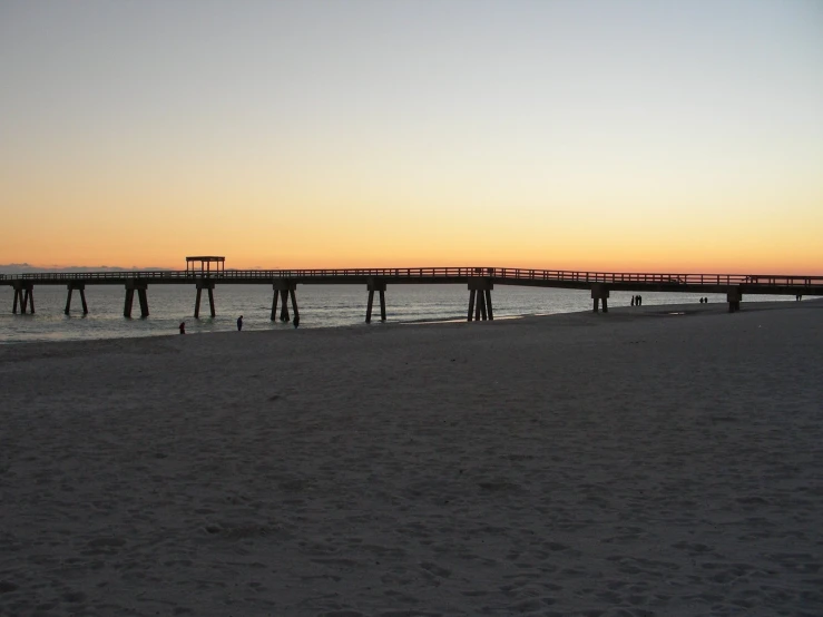 the long pier is at the beach during sunset