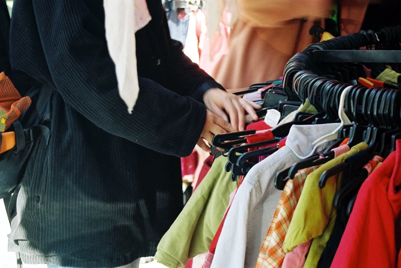 a woman standing next to an rack full of clothes