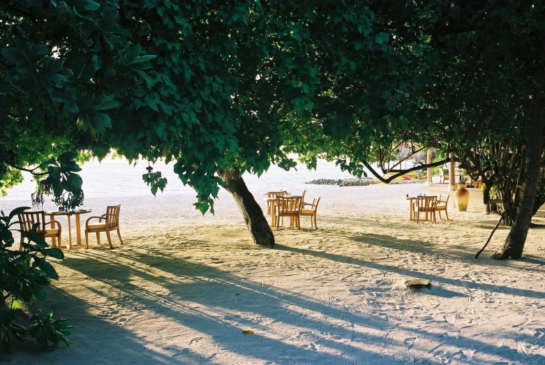 a table and chairs are on the sandy beach