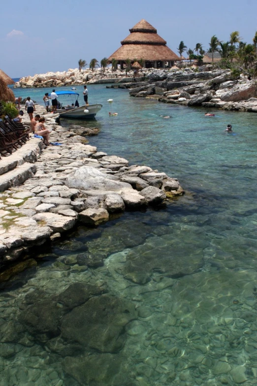 people enjoying an outdoor pool with a hut on the background