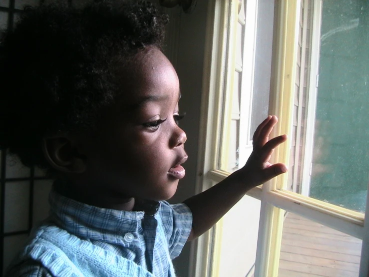 a small child standing next to a window