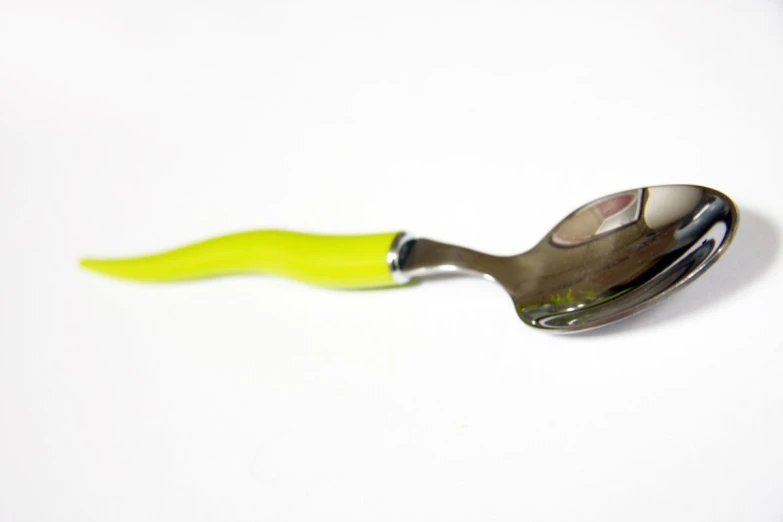 a small yellow spoon holding a shiny metal spoon