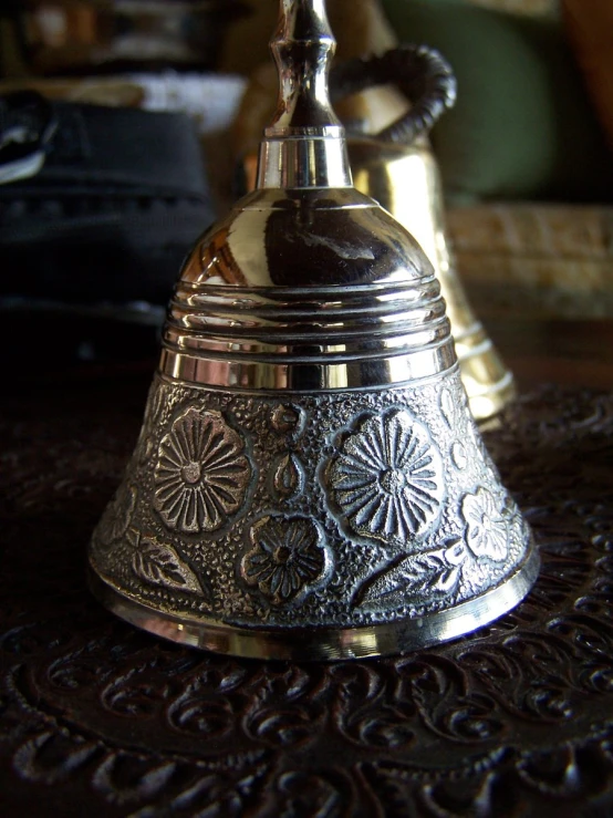 a silver bell sitting on top of a table