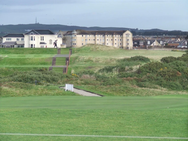 the view of a green course and a large building