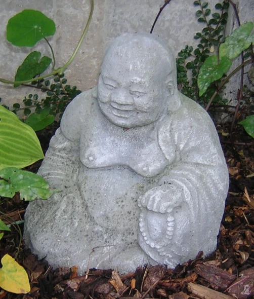 a statue of a sitting buddha rests in a bush
