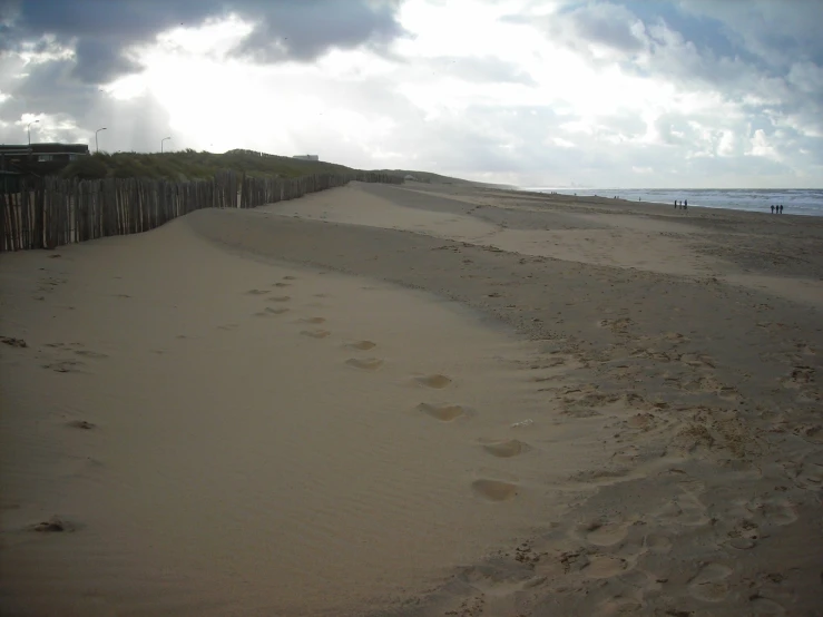 a sandy beach with footprints and fences along the sand