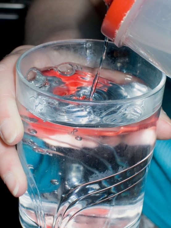 a person is pouring water into a glass