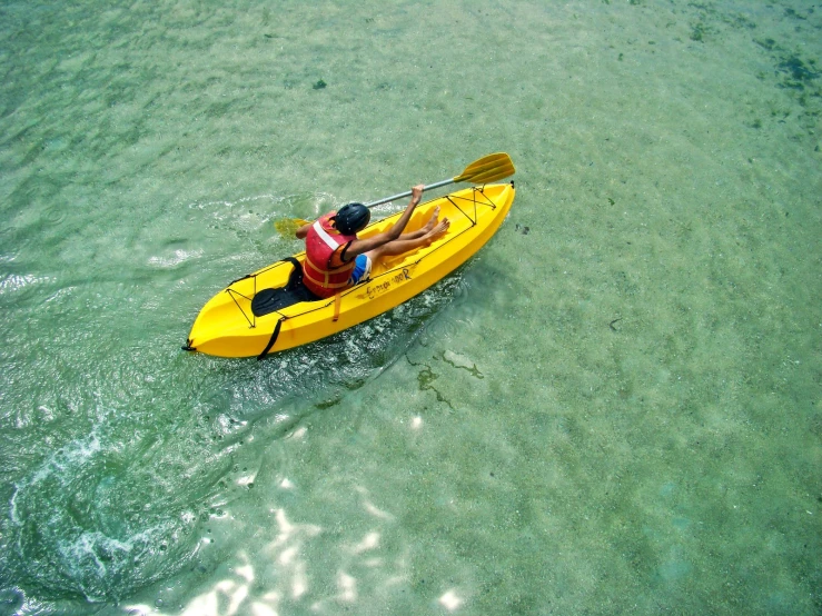 a man wearing red sitting in a yellow kayak