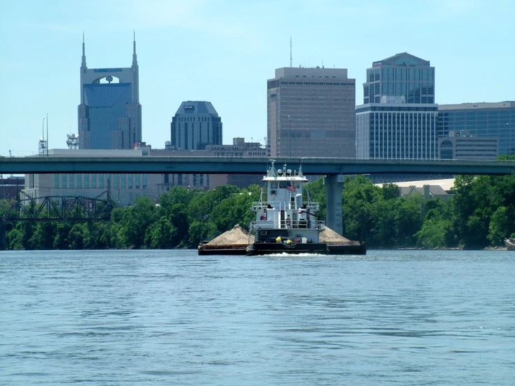 a tug boat is moving in front of a city with skyscrs