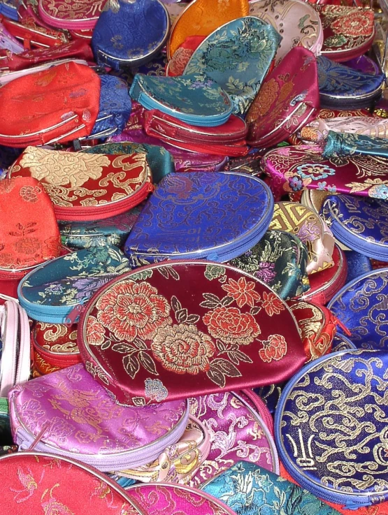 a pile of colorful purses and mirrors are stacked together