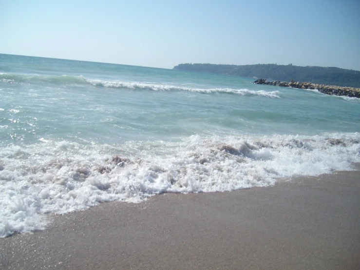 the sea water is splashing onto the sand