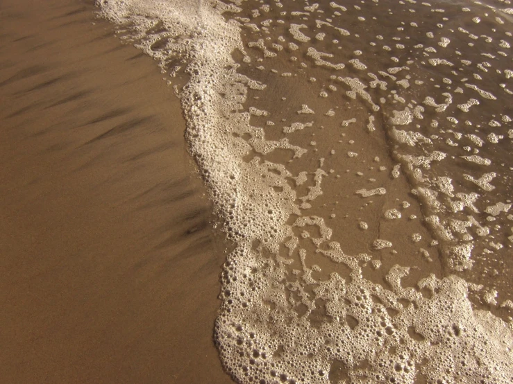 waves are rolling in on the sandy beach