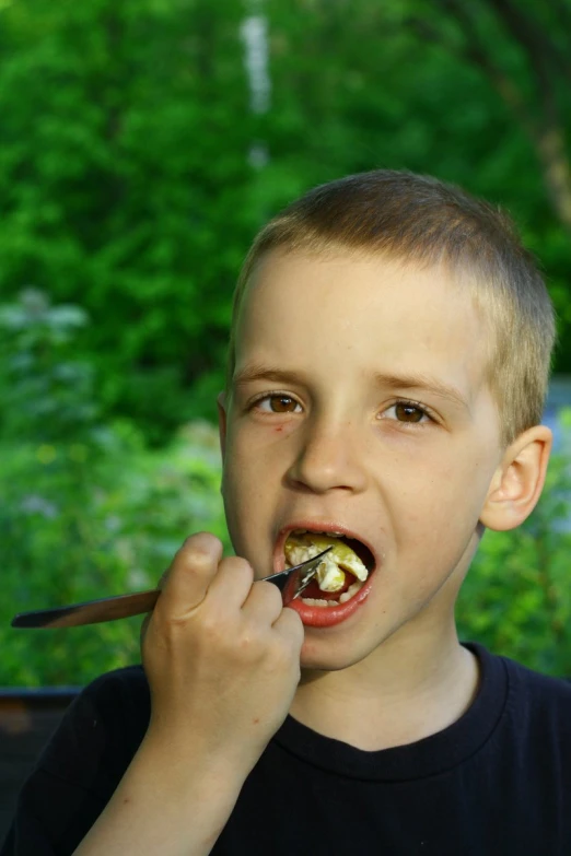 a boy has food in his mouth and spoon in his mouth