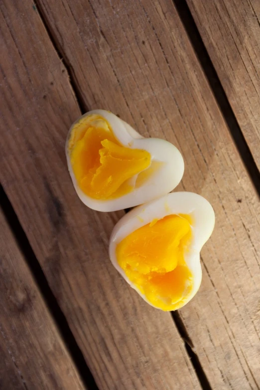 two hard boiled eggs sitting on a wooden table