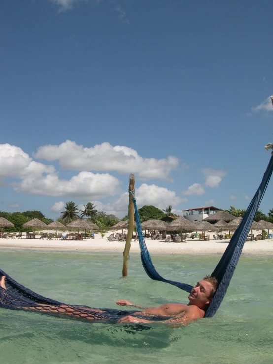 a man relaxing in a hammock near the beach