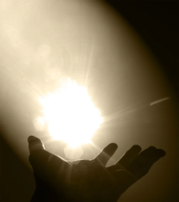 the sun shining on someones hand as he reaches out