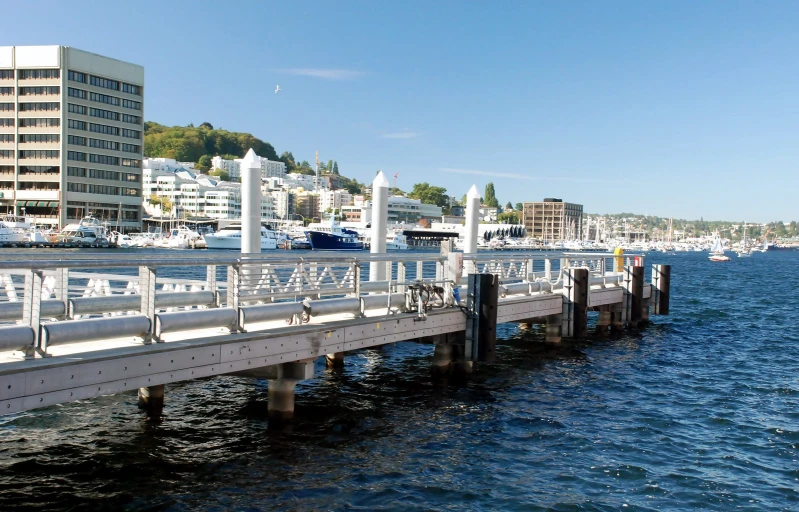 a white long walkway is leading to a pier with many boats in it