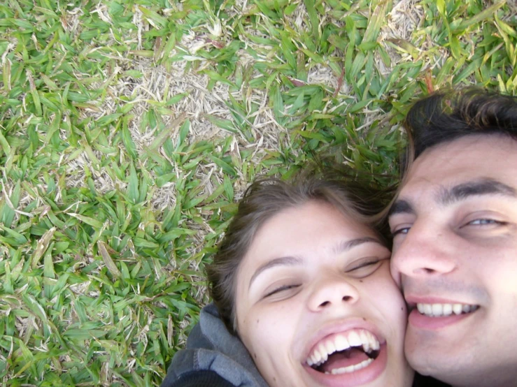 a woman and man laying on the ground, having fun