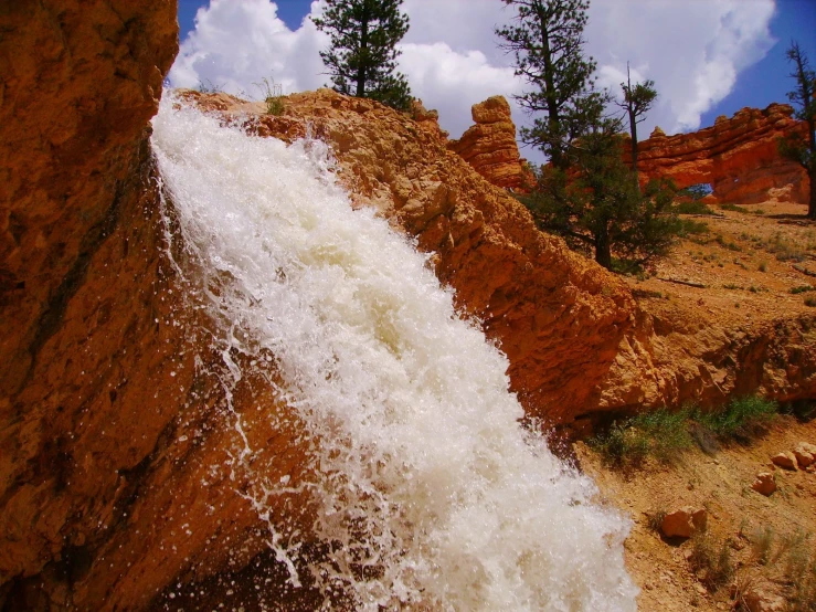 a water fall coming out of the middle of an orange rock