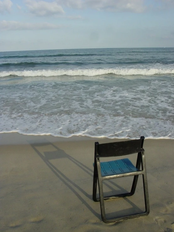 a beach chair with a blue pad attached to it near the water