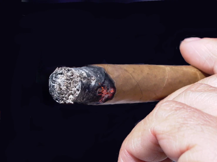 someone holding their fingers and pointing at the edge of a cigar