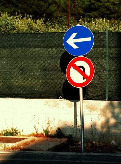 two street signs in front of a fence
