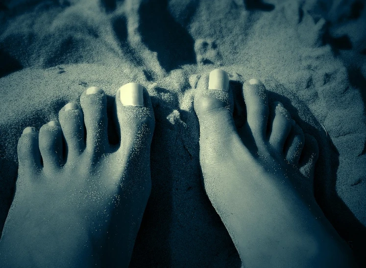 the feet and ankles of someone laying in the sand
