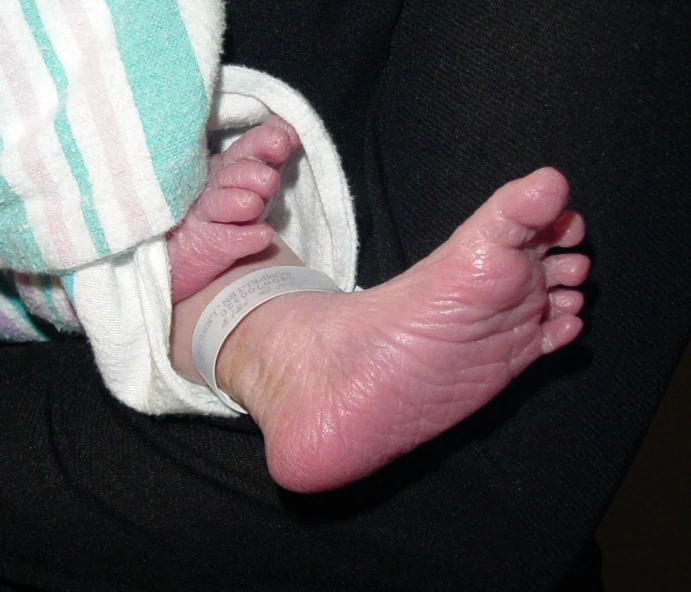 a baby's bare feet and leg in a blanket