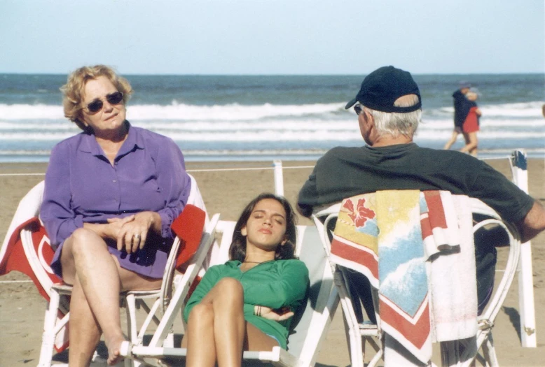 a woman and man sitting in lawn chairs on a beach