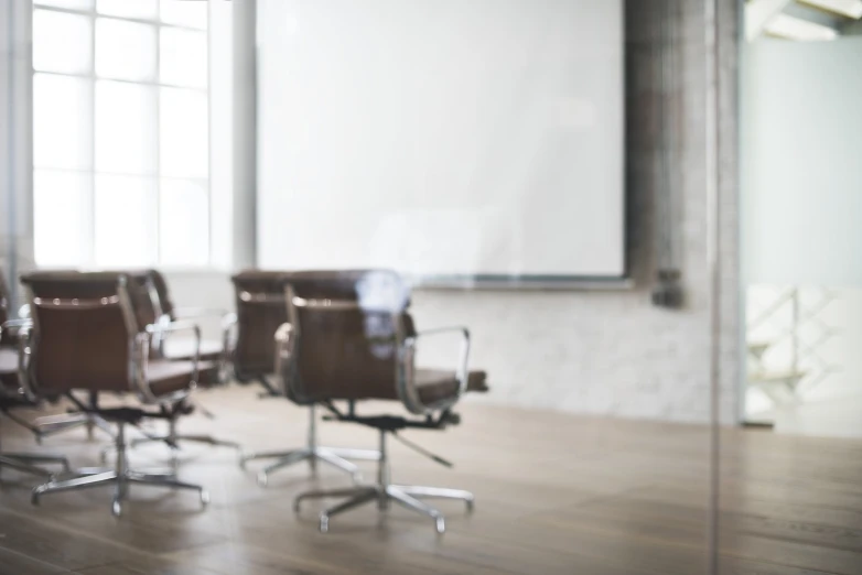 an empty conference room with multiple chairs in front of a projector screen