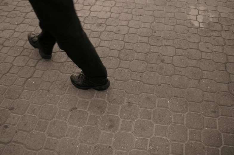 the foot and legs of a person walking along a street