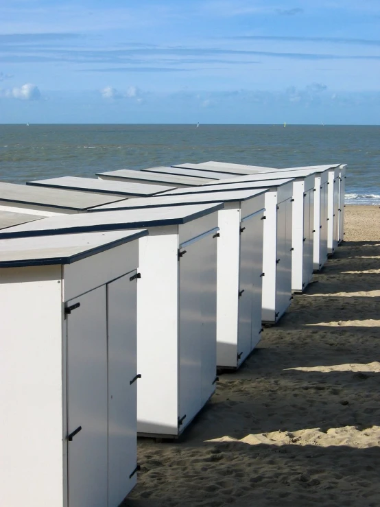a row of outhouses on the beach in front of the water