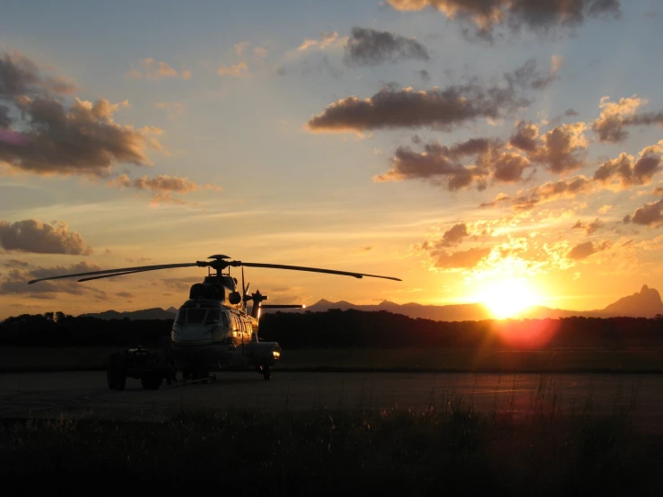 a helicopter sitting on the ground at sunset
