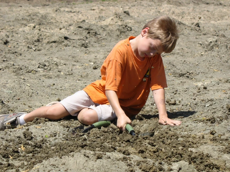a  sitting in the sand and digging into some dirt