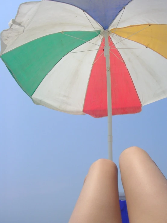 a person has their legs underneath a colorful umbrella