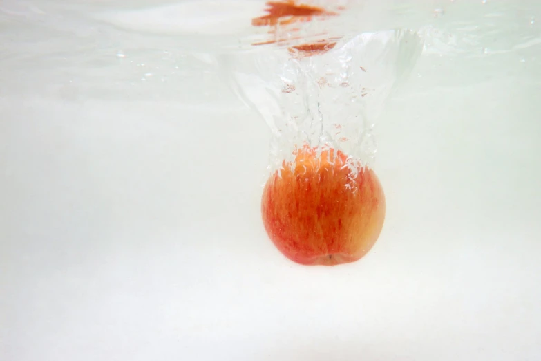 a small red apple sits in a clear water