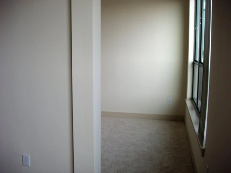 an empty room with a window and wall on the other side