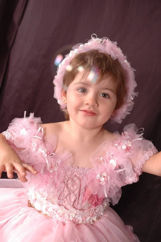 a little girl in a pink dress with a light shining in her face