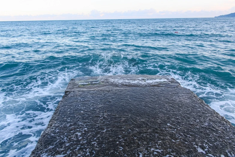 a pier in the water at dusk with waves crashing against it