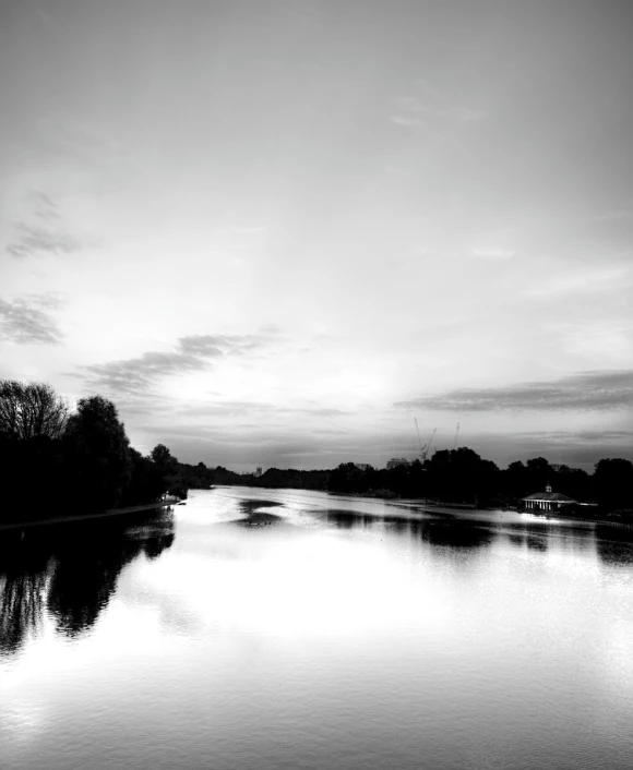 an empty river sits between some trees and clouds