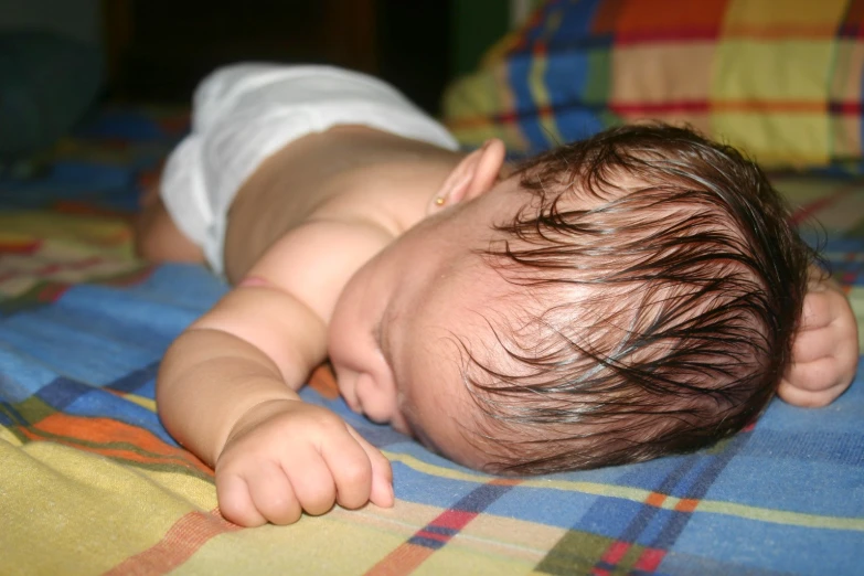 a close up of a baby laying on a bed