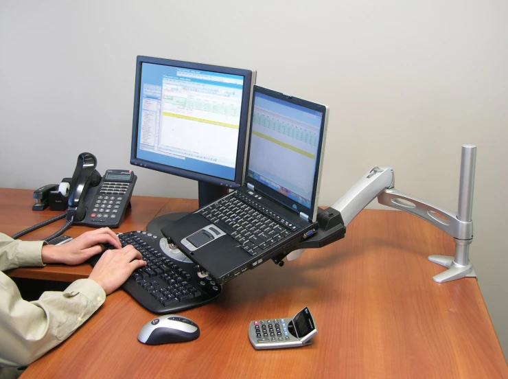 a person that is using his lap top while talking on the phone